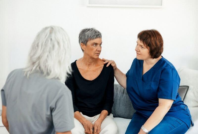 Drei Personen im Gespräch. Patientin wird durch Pflegedienst betreut und dieser durch Wundversorgerin zur Behandlung angeleitzet.