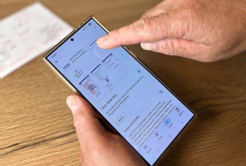 Die RezeptApp wird von einer Person auf einem Smartphone heruntergeladen