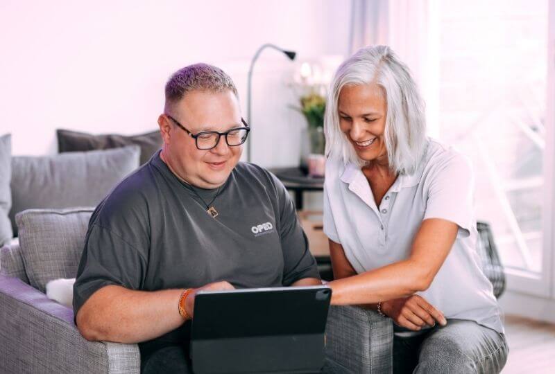 Zwei Personen im Gespräch vor einem Tablet.