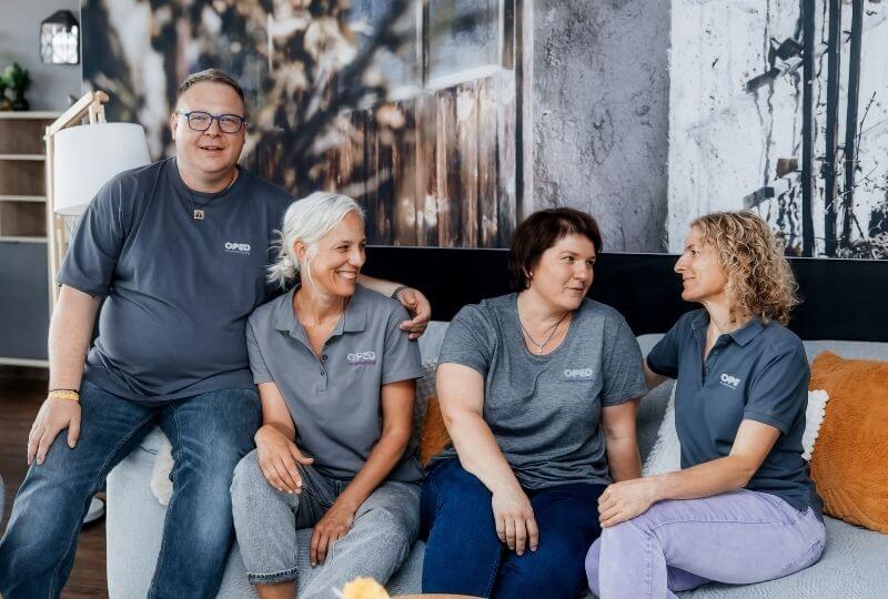 Karriere bei OPED Wundversorgung: Bild mit vier lachenden Mitarbeitenden von OPED Wundversorgung,, die auf einem Sofa in einem modernen Raum sitzen.