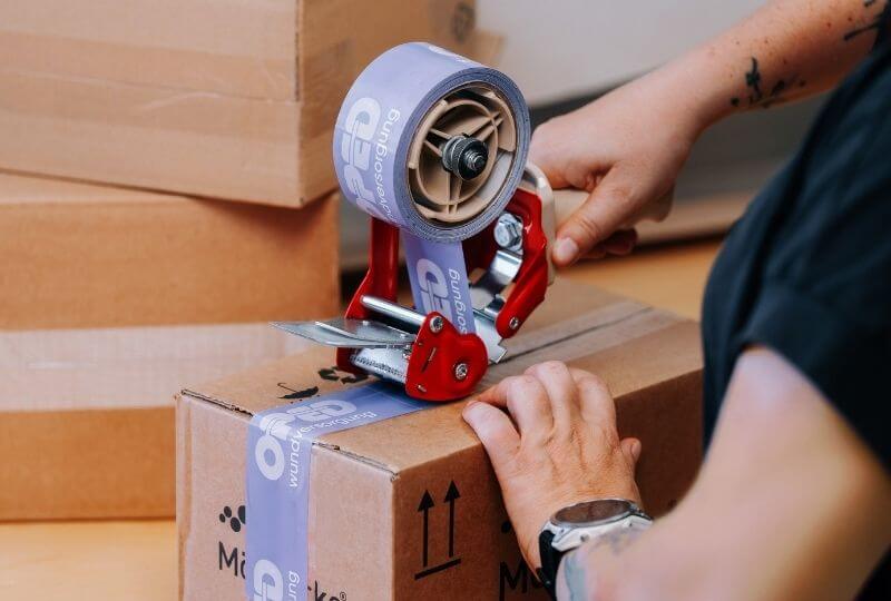Mitarbeiterin in der Logistik verpackt ein Paket für den Warenversand bei OPED Wundversorgung an die Wunschadresse des Kunden.