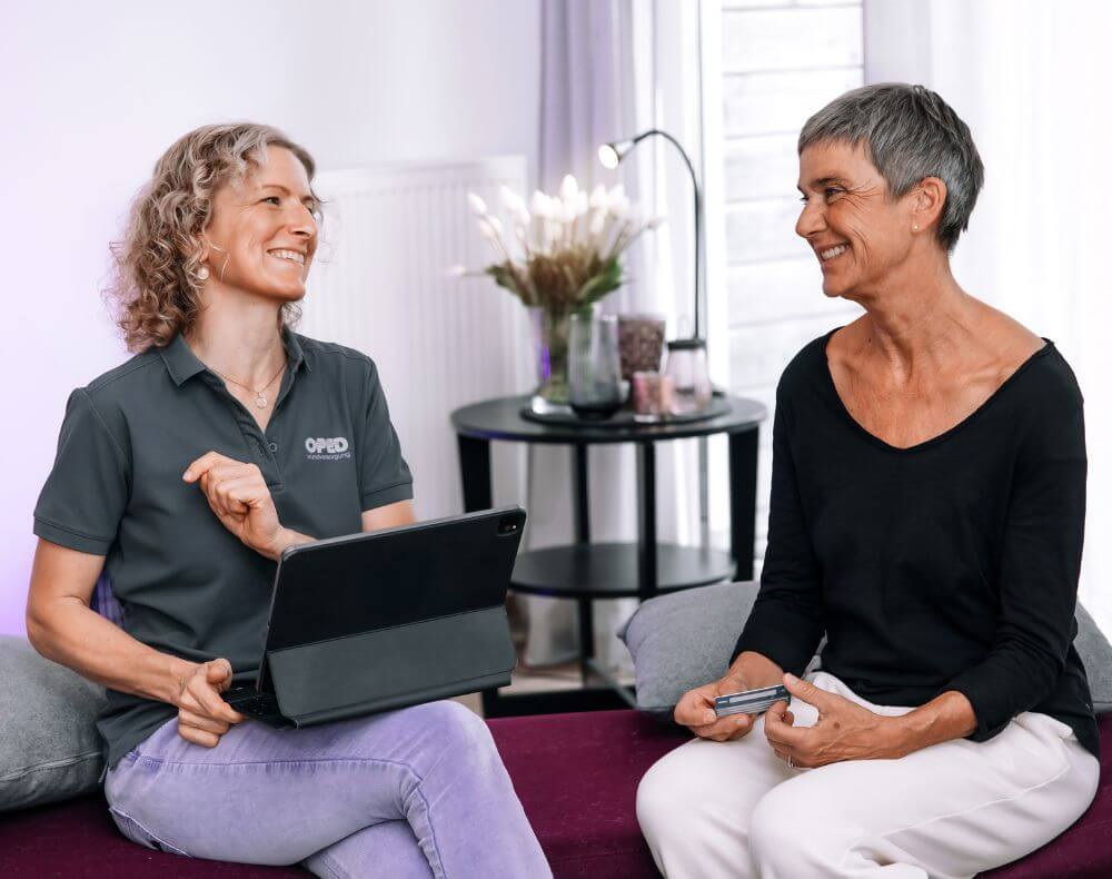 Die Wundversorgerin berät eine Patientin im persönlichen Gespräch mit einem Tablet. Die OPED Wundversorgung ermöglicht eine individuelle, moderne Wundversorgung im häuslichen Umfeld.