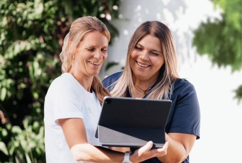Zwei Frauen - eine Mitarbeiterin der OPED Wundversorgung spricht über das Unternehmen. Beide stehen draußen und schauen während des Gesprächs auf das Tablet, dass eine von ihnen in der Hand hält.