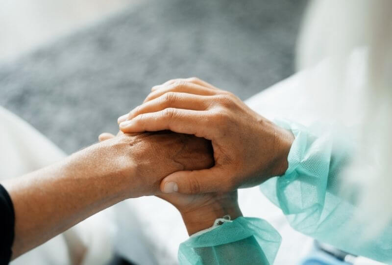 Wundversorgerin hält die Hand einer Patientin im heimischen Umfeld