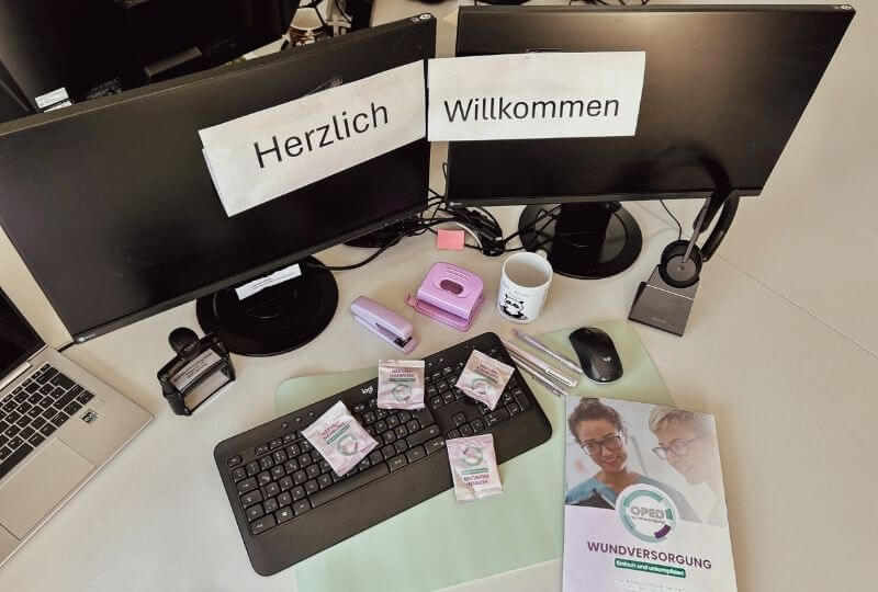 Ein Bild von einem Arbeitsplatz mit zwei Bildschirmen. Der Platz wurde mit "Herlich Willkommen" und ein paar Süßigkeiten dekodiert, um einen neuen Kollegen willkommen zu heißen.