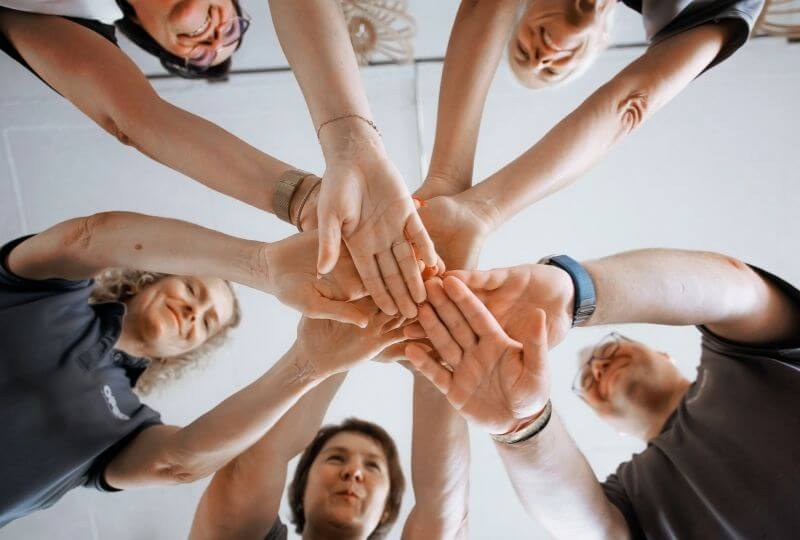 Teamfoto von Mitarbeitenden von OPED Wundversorgung. Sie halten die Hände in der Mitte zusammen.