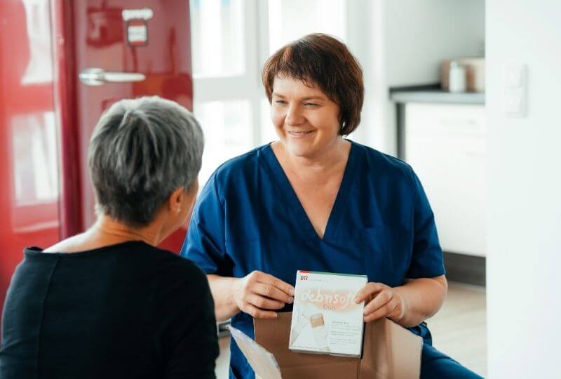 Mitarbeiterin vom Pflegedienst/Pflegeheim kümmert sich um Patientin