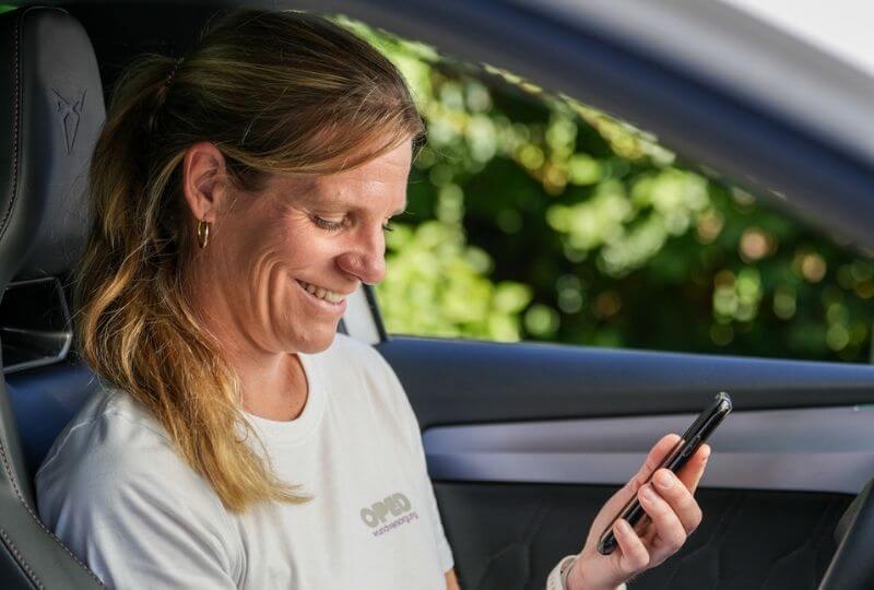 Wundversorgerin von OPED Wundversorgung im Auto mit Smartphone in der Hand