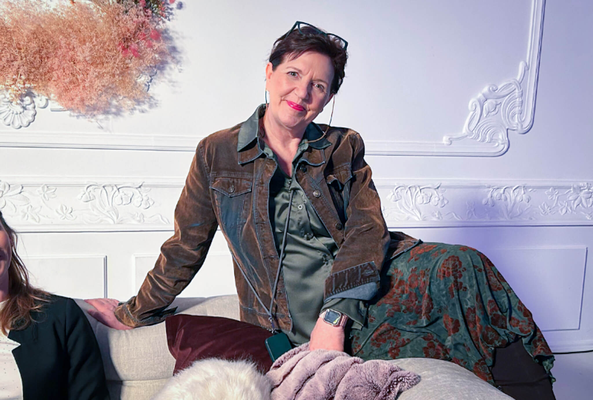 Unsere Kollegin Ulrike Wagner, fachliche Leitung Wundversorgung, sitzt auf einer Coucklehne und lächelt in die Kamera.